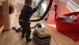 Ein Kind Hilft im Haushalt indem es sein Kinderzimmer gerne selbst saugt.