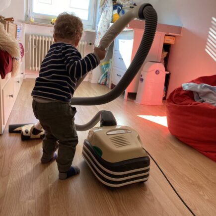Ein Kind Hilft im Haushalt indem es sein Kinderzimmer gerne selbst saugt.