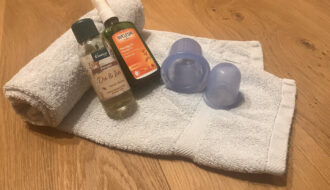 Silikon-Cups und Massageöl auf einem Handtuch – Material zum Schröpfen zuhause