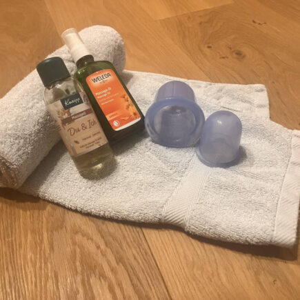 Silikon-Cups und Massageöl auf einem Handtuch – Material zum Schröpfen zuhause