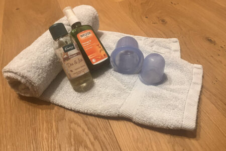 Silikon-Cups und Massageöl auf einem Handtuch – Material zum Schröpfen zuhause