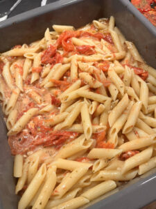 Penne mit Ofentomaten und Käse vermengt in der Auflaufform