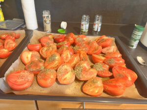 Rohe Tomatenspalten mit Olivenöl, Salz und Kräutern auf einem Blech